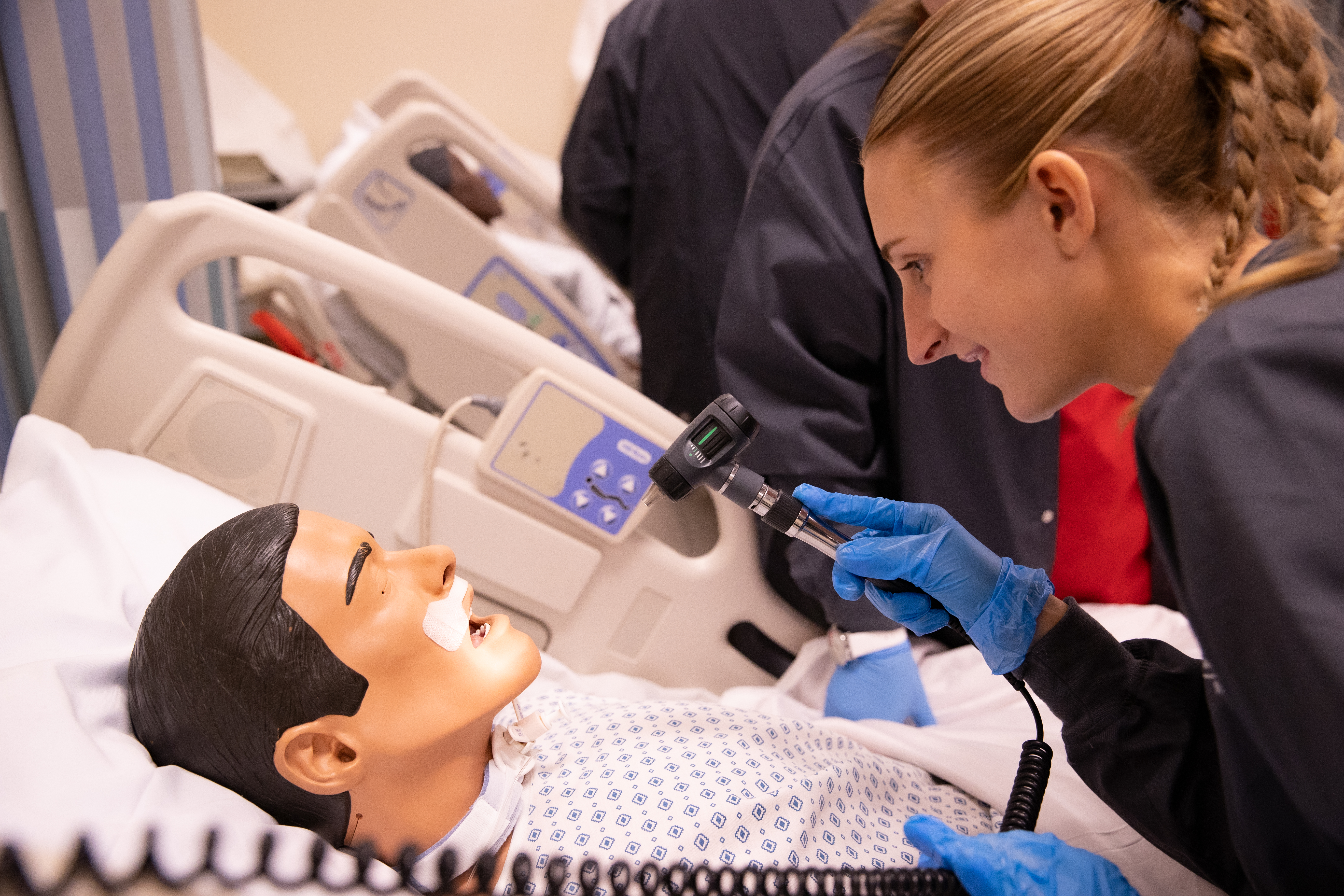 Nursing student looking into the mouth of a mannequin 