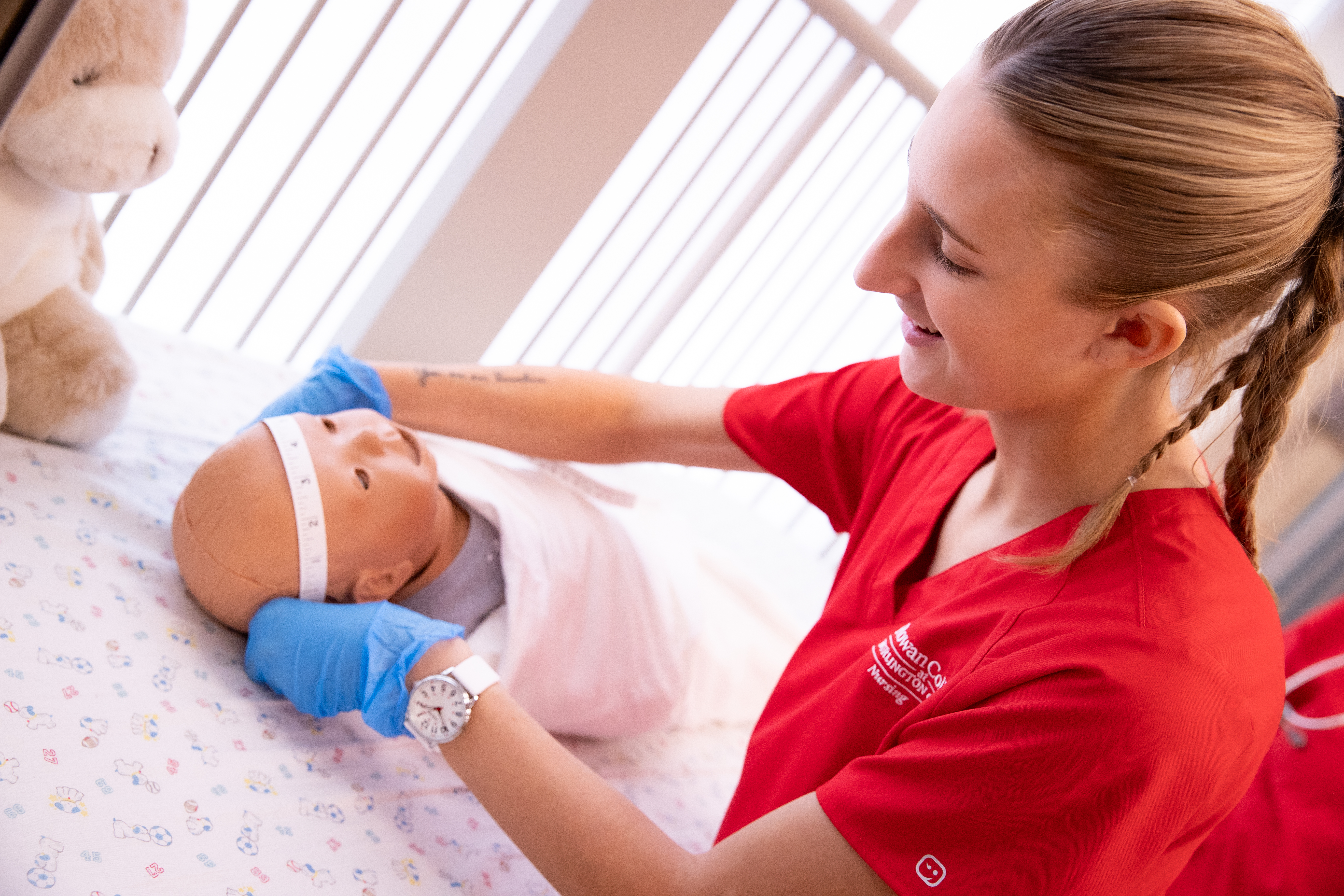 Nursing student measuring the circumference of a baby doll head