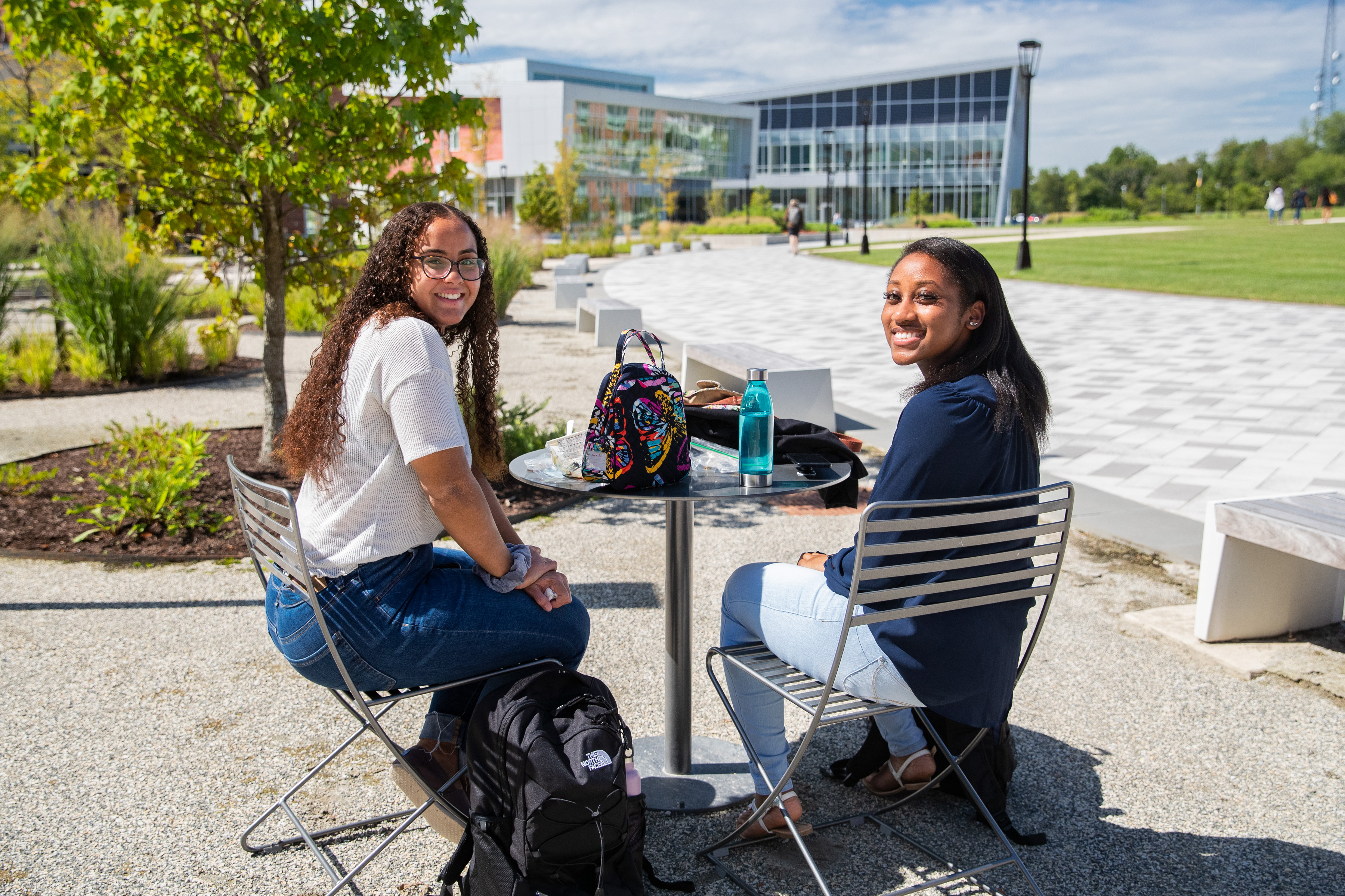 two female students sitting at table in quad area