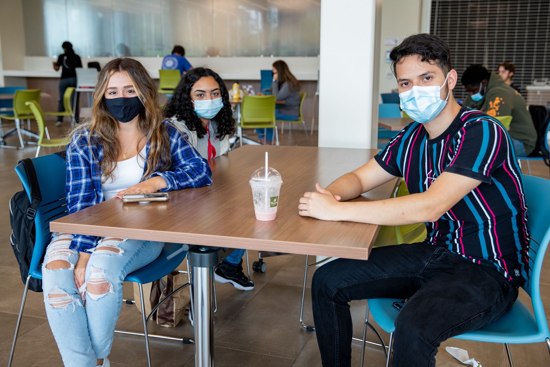 three students sitting around a table in the cafeteria