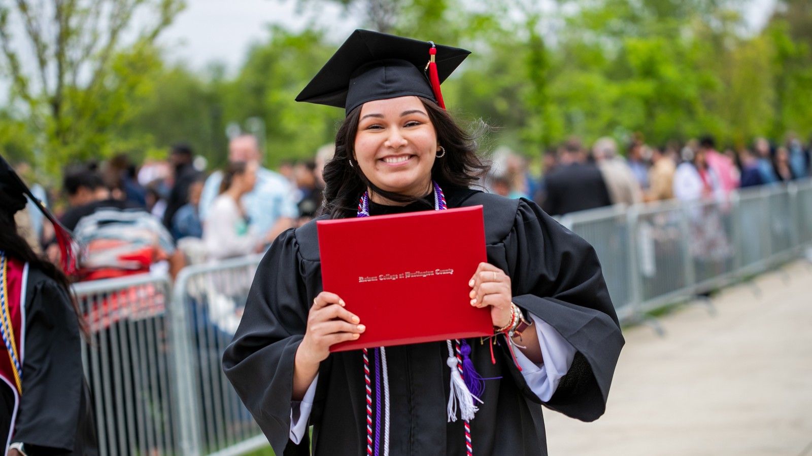 Hispanic female student holding her diploma at graduation