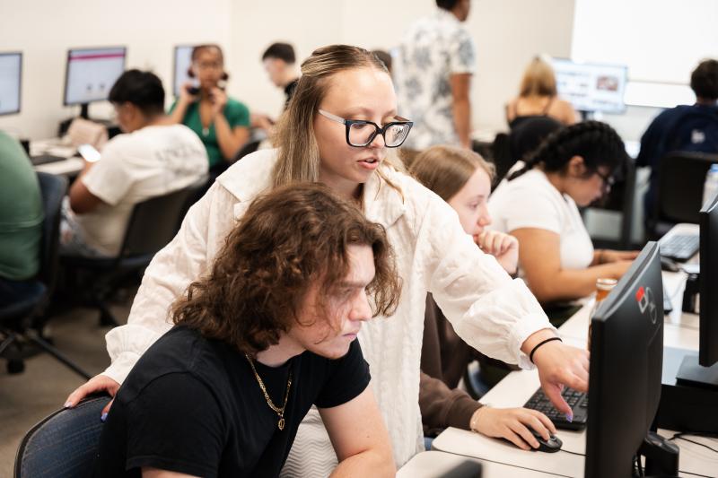 EOF student looking at computer screen with teacher over the shoulder assisting the student