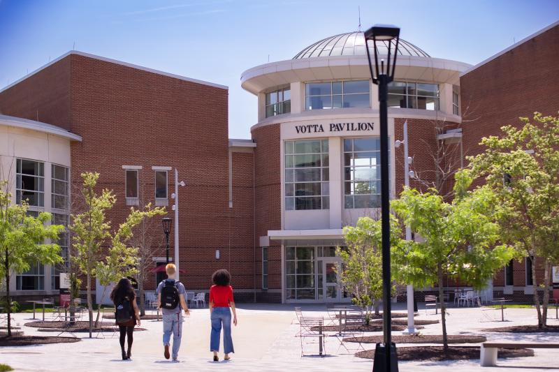 Three students walk toward Votta Hall pavilion