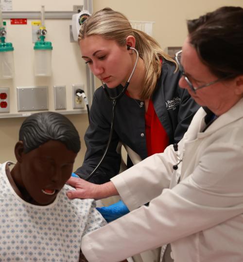 RCBC Health Science student using a stethoscope on dummy while a teacher holds it up