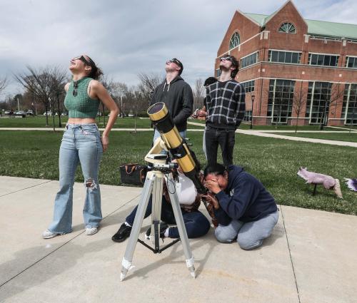 Physics students using a telescope to see solar eclipse