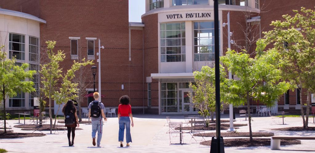 Three students walk toward Votta Hall pavilion