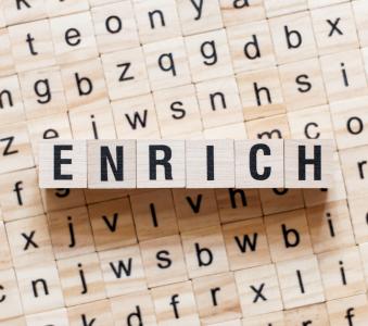 Wooden alphabet blocks spelling the word enrich