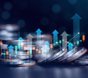 A pile of quarters with stock market graphic arrows pointing up