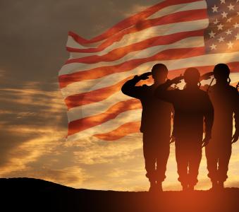 Three soldiers saluting with American Flag in the background