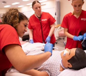 Three RCBC Health Sciences students practicing on a dummy