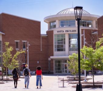 Three students walk toward Votta Hall pavilion