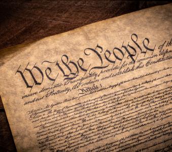 A copy of the Constitution of the United Sates of American on a wooden background