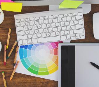 Modern office workplace with digital tablet, notepad, colorful pencils, glasses, in morning