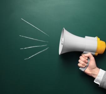 Man holding megaphone near chalkboard