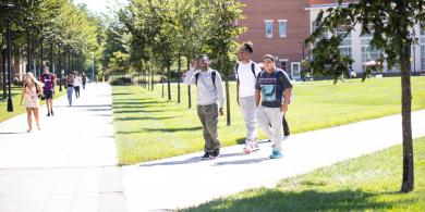 Three students walk together through the quad.