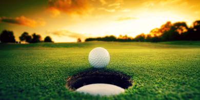 Golf ball next to a hole on the golf course