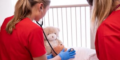 Nursing students using a stethoscope on a baby doll