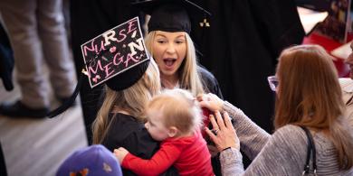 Nursing student wearing a cap stating "Nurse Megan" at winter commencement with family 