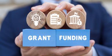 Man holding colorful blocks with icons and inscription: GRANT FUNDING. Concept of grants and funding.