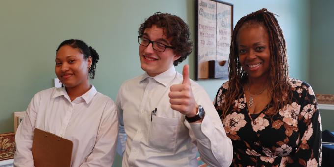 Three RCBC students behind hostess desk at Vaulted Cuisine Restaraunt
