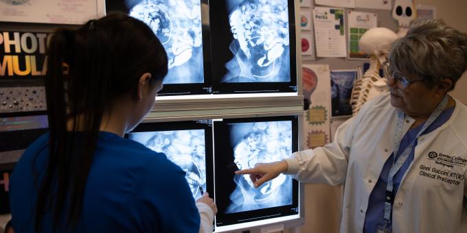 A radiography professor looks over an X-ray with a student.