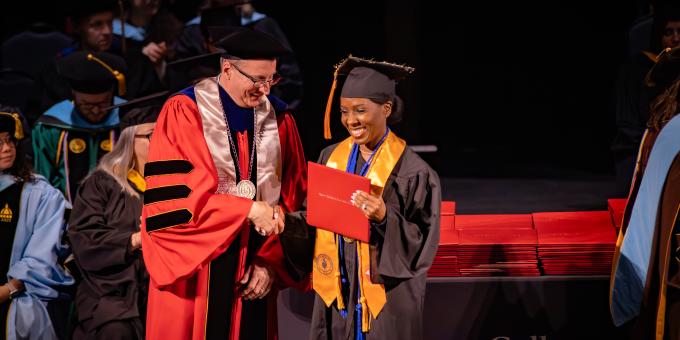 A student poses with their diploma.
