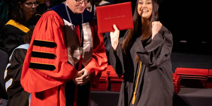 An RCBC graduate celebrates at commencement with her diploma.