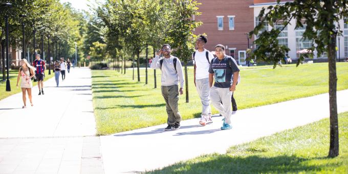 Three students walk together through the quad.