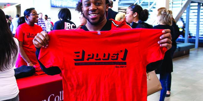 A student smiles with a 3+1 t-shirt on 3+1 day in the SSC.