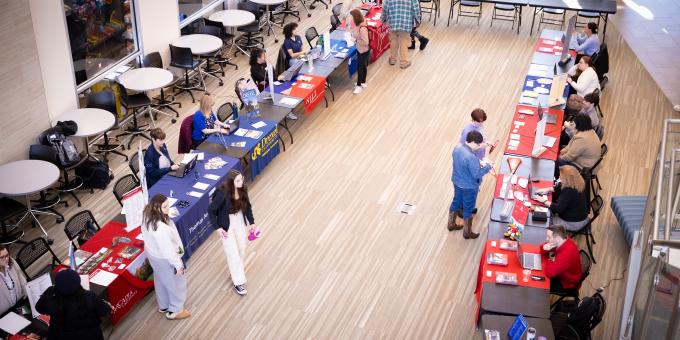 Various college university tables lined up the SSC lobby for Transfer Fair. 