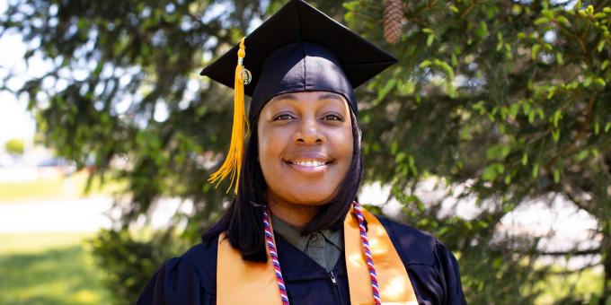President's Award winner Ariel Howard poses outside in her graduation regalia.