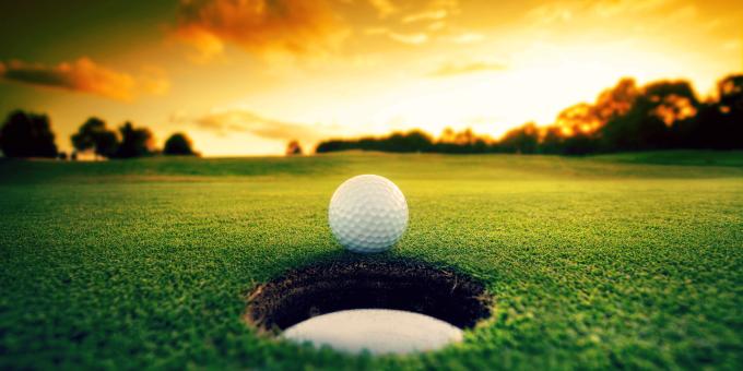 Golf ball next to a hole on the golf course