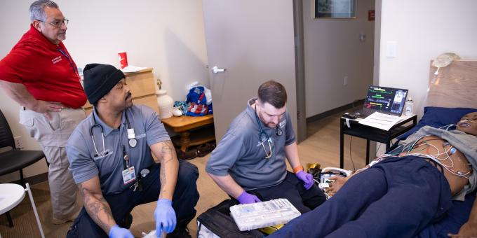 RCBC EMT students participating in a simulation with an instructor looking on.