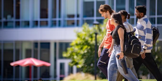 Four RCBC student models walking across the quad smiling