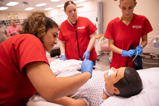 Three RCBC Health Sciences students practicing on a dummy