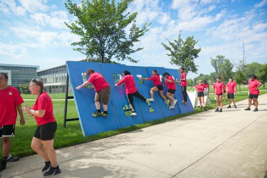 Pre-College Learning Institute attendees climbing a blue wall