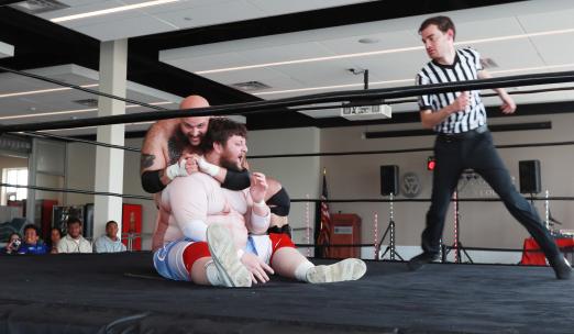 Two wrestlers in a ring with a referee