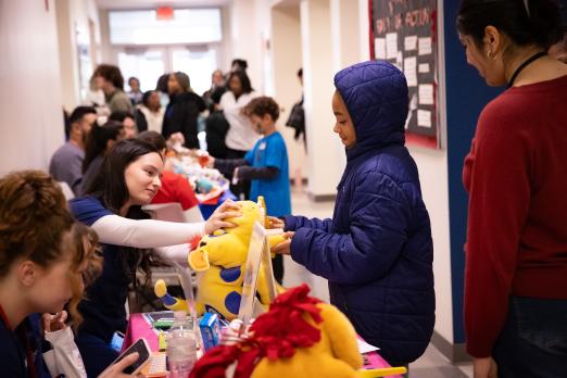 A child receiving a stuffed animal from a dental vendor table