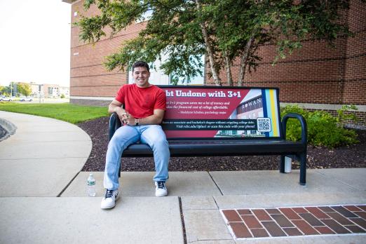 Student model Michael Caulder sits on a bench on campus.