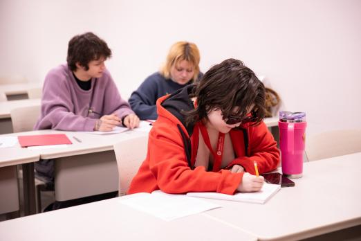 Students writing notes in their notebook with pencils