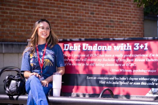 Student model Soshyl Narvaez sits on a bench on campus.