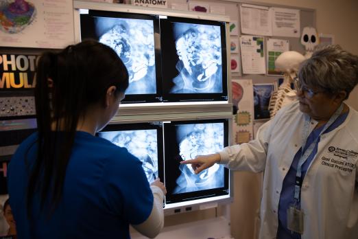 A radiography professor looks over an X-ray with a student.