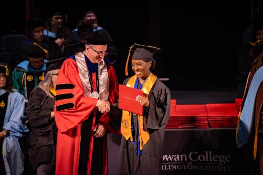 A student poses with their diploma.