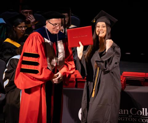 An RCBC graduate celebrates at commencement with her diploma.