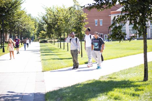 Three students walk together through the quad.