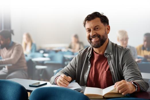 Adult student smiling at desk with open book