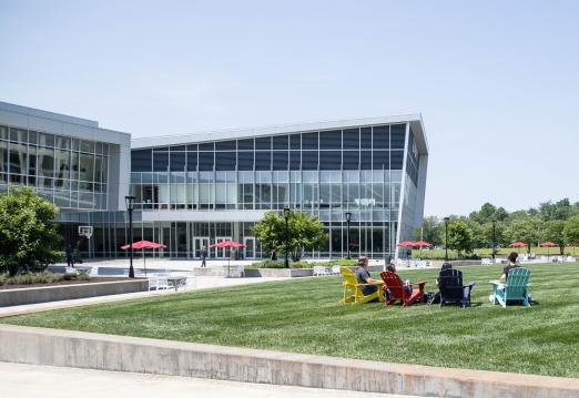 Four RCBC students sit on the quad outside the SSC on BOLD colored chairs