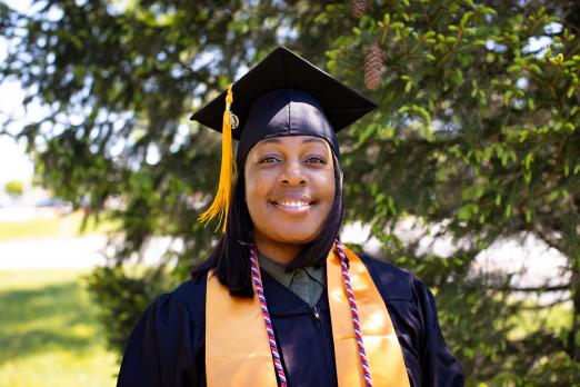 President's Award winner Ariel Howard poses outside in her graduation regalia.