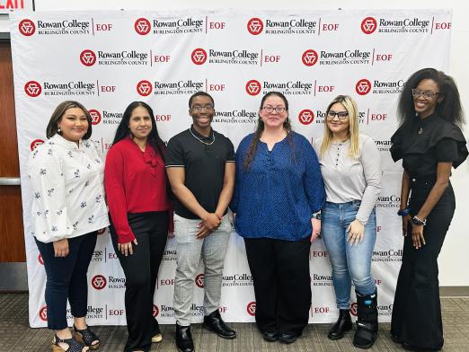 EOF Alumni students posing in front of RCBC step and repeat canvas