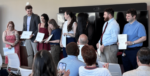 Eight Spring 2026 paramedic graduates stand with their diplomas.
